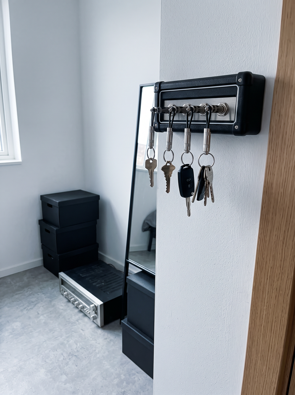 A guitar amp key holder with plug keychains on a wall by the door
